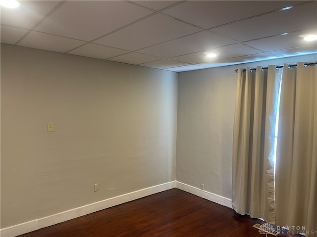 spare room featuring dark hardwood / wood-style floors and a drop ceiling