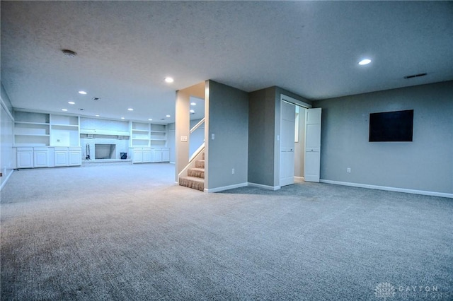 unfurnished living room featuring built in features, a textured ceiling, and carpet flooring