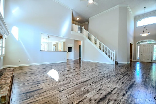 unfurnished living room featuring a high ceiling, hardwood / wood-style floors, and crown molding