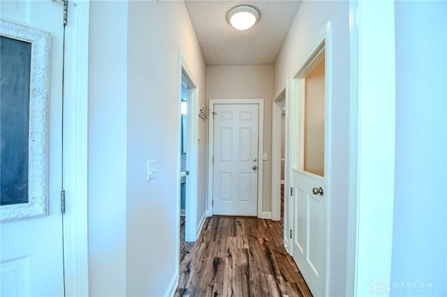 hall with wood-type flooring and a textured ceiling