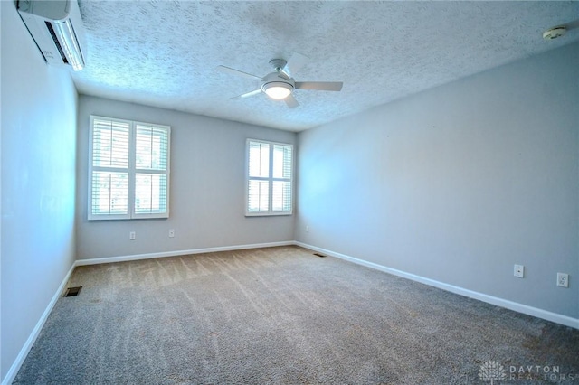 carpeted empty room with a textured ceiling, ceiling fan, and an AC wall unit