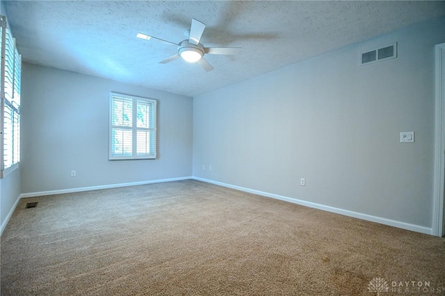 carpeted spare room with ceiling fan, a textured ceiling, and a wealth of natural light