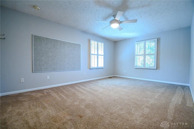 carpeted spare room featuring ceiling fan and a textured ceiling