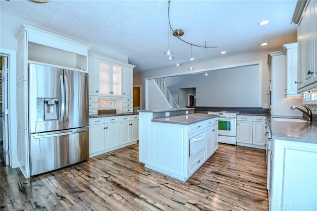 kitchen featuring electric stove, sink, stainless steel fridge with ice dispenser, and white cabinetry