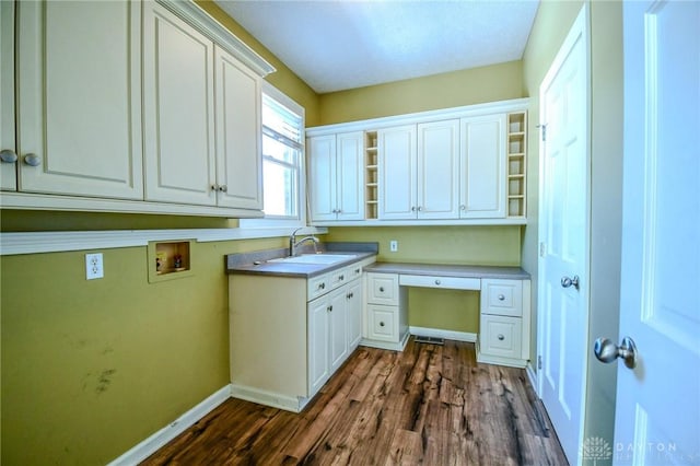 laundry area featuring dark hardwood / wood-style flooring, sink, hookup for a washing machine, and cabinets