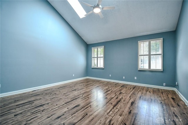 empty room featuring ceiling fan, a skylight, hardwood / wood-style floors, and high vaulted ceiling