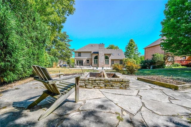 rear view of property with an outdoor fire pit, a yard, and a patio