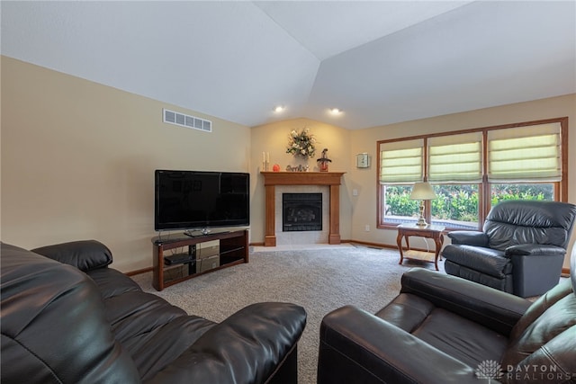 living room with a tiled fireplace, vaulted ceiling, and carpet