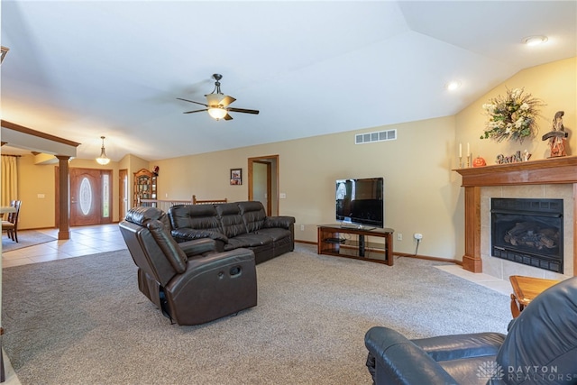 carpeted living room with decorative columns, a tile fireplace, lofted ceiling, and ceiling fan