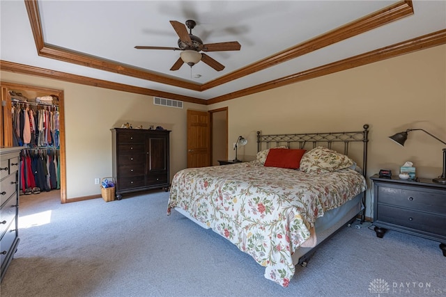 bedroom with a walk in closet, ornamental molding, and a tray ceiling