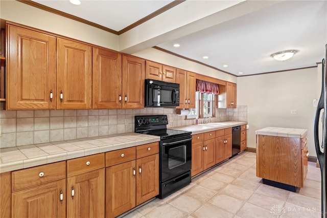 kitchen featuring sink, a kitchen island, tile countertops, light tile patterned flooring, and black appliances