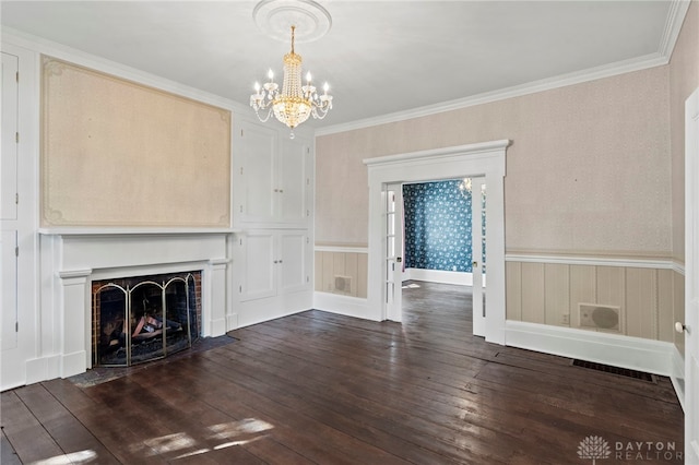 unfurnished living room with a fireplace, ornamental molding, dark wood-type flooring, and an inviting chandelier