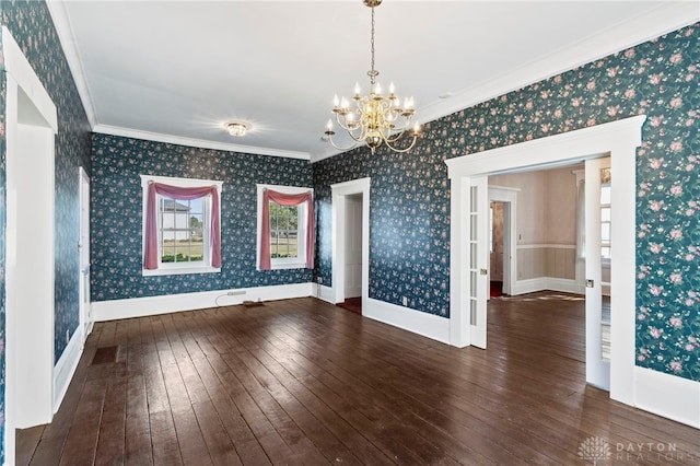 spare room featuring a notable chandelier, crown molding, and dark wood-type flooring