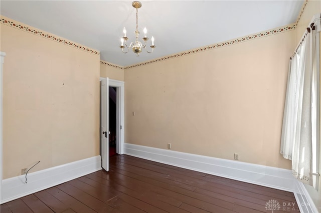 empty room featuring a chandelier and dark wood-type flooring