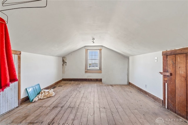 additional living space featuring lofted ceiling and light wood-type flooring