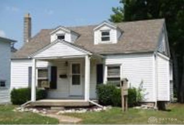 new england style home featuring a front yard and a porch