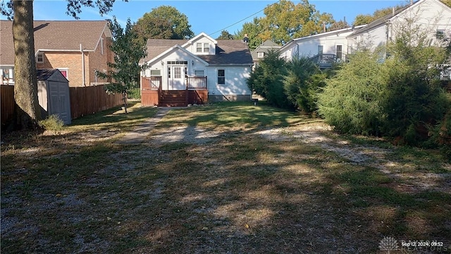 view of yard with an outbuilding, a shed, a wooden deck, and fence