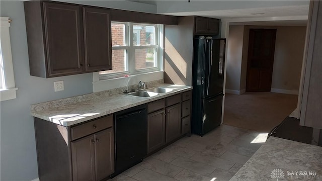 kitchen featuring a sink, baseboards, black appliances, and light countertops