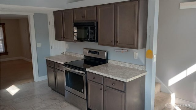 kitchen featuring dark brown cabinets, baseboards, black microwave, stainless steel electric range oven, and light countertops