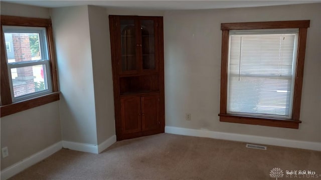 unfurnished dining area with baseboards, visible vents, and light carpet