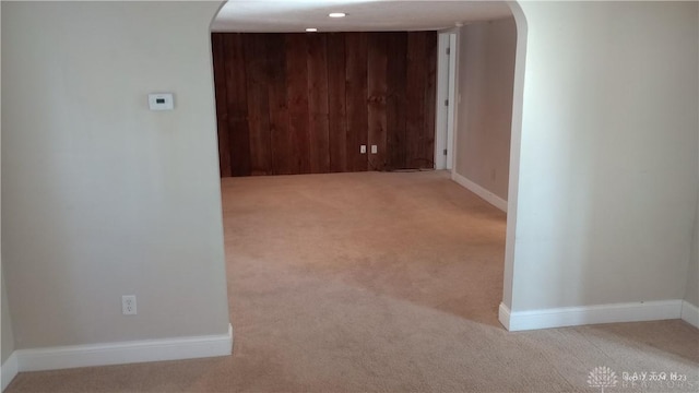 hall with wooden walls and light colored carpet