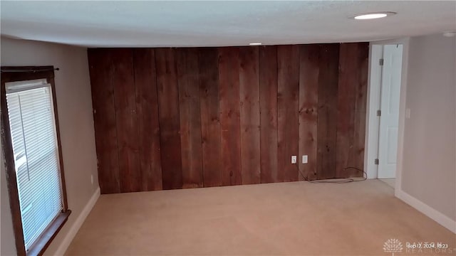 carpeted spare room with wooden walls