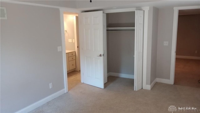 unfurnished bedroom featuring a closet, baseboards, and light colored carpet