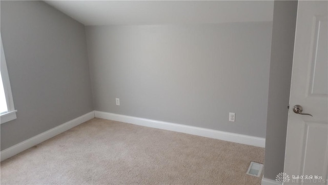 empty room featuring light colored carpet and lofted ceiling