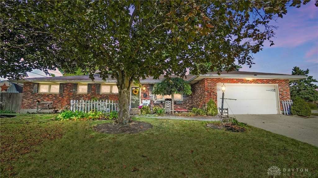 single story home featuring a lawn and a garage