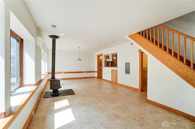 unfurnished living room with a wall unit AC, electric panel, and a wood stove