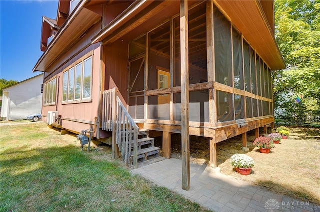 view of side of home with a yard, a patio, and a sunroom