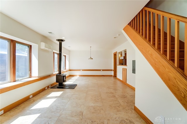 interior space featuring electric panel, a wood stove, and a wall mounted air conditioner