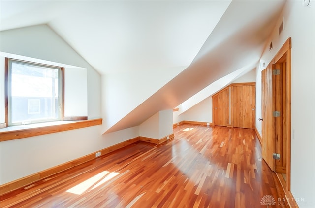 additional living space featuring light wood-type flooring and lofted ceiling