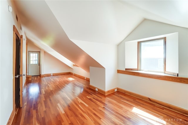 additional living space with hardwood / wood-style floors and vaulted ceiling