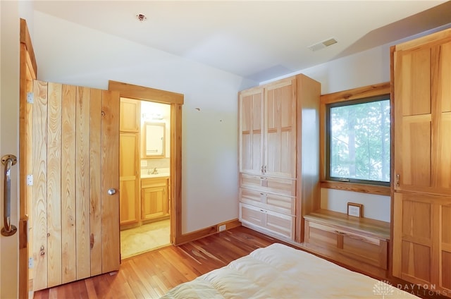 bedroom with light hardwood / wood-style flooring and connected bathroom