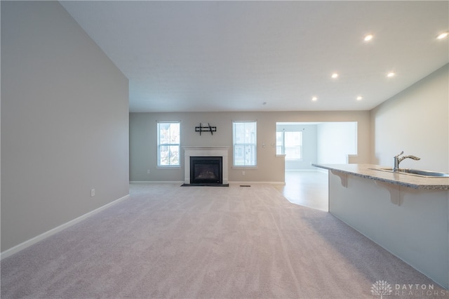 unfurnished living room with light carpet and sink