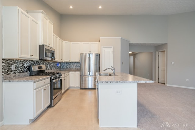 kitchen featuring white cabinets, stainless steel appliances, a center island with sink, and sink