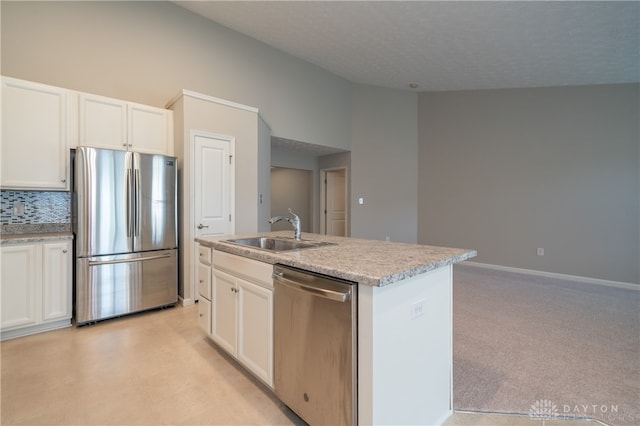 kitchen with white cabinets, appliances with stainless steel finishes, an island with sink, and sink