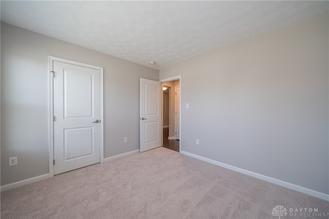 unfurnished bedroom featuring a textured ceiling and light carpet