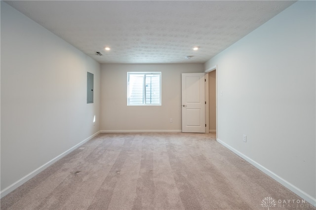 unfurnished room featuring electric panel, light colored carpet, and a textured ceiling