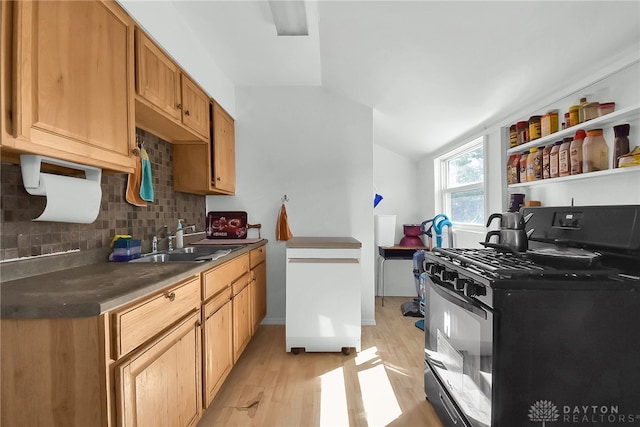 kitchen featuring vaulted ceiling, light hardwood / wood-style flooring, gas range oven, tasteful backsplash, and sink