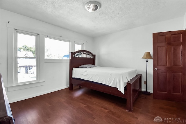 bedroom with multiple windows, a textured ceiling, and dark wood-type flooring