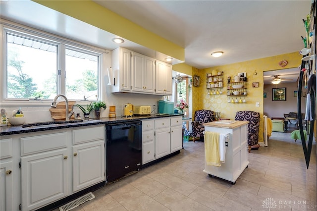 kitchen featuring ceiling fan, sink, white cabinets, black dishwasher, and light tile patterned flooring