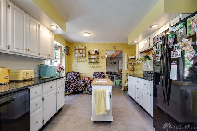 kitchen with dark stone counters, black appliances, white cabinets, light tile patterned floors, and tasteful backsplash