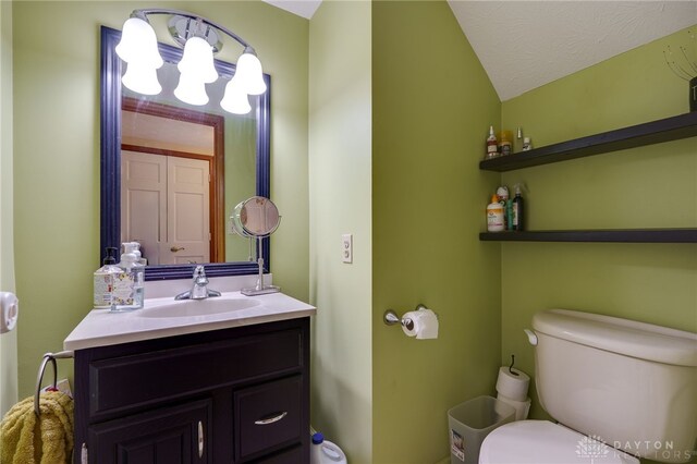 bathroom featuring vanity, toilet, lofted ceiling, and a textured ceiling