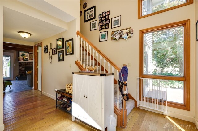 stairs featuring a stone fireplace, wood-type flooring, and a wealth of natural light