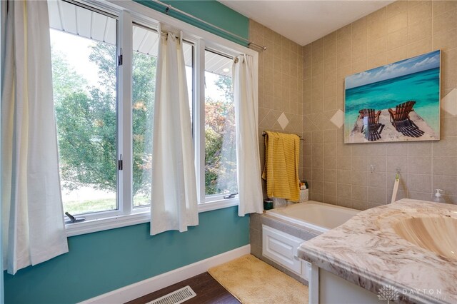 bathroom featuring hardwood / wood-style flooring, vanity, plenty of natural light, and a bath