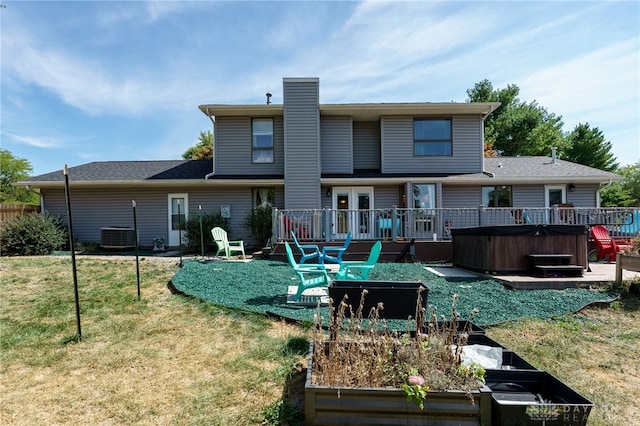 back of house featuring a lawn, a hot tub, and a deck