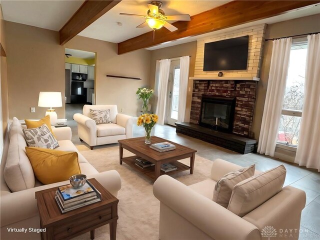 living room with ceiling fan, a fireplace, and beamed ceiling