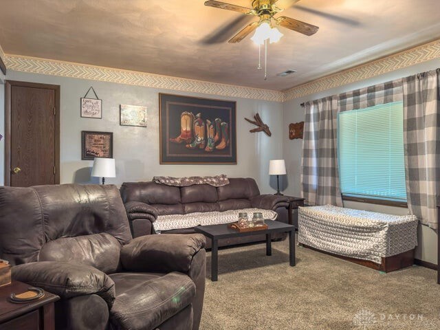 living room with ceiling fan and carpet